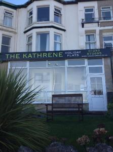 una panchina di fronte a un edificio con un cartello di The Kathrene Holiday Flats a Fleetwood