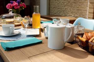 a wooden table with a wooden table with food and drinks at Safranière de la Venelle du Moulin in Jort