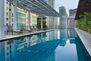 a hotel swimming pool with chairs and buildings at Ascott Kuala Lumpur in Kuala Lumpur