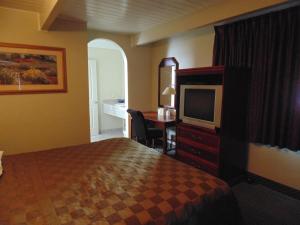 ein Hotelzimmer mit einem Bett, einem TV und einem Schreibtisch in der Unterkunft Marina Inn in Berkeley