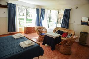 sypialnia z 2 łóżkami, krzesłami i oknami w obiekcie Hostería Chimehuin w mieście Junín de los Andes