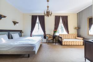 Hotel Fryderyk في دوشنيكي زدروي: غرفة نوم بسرير واريكة وكرسي