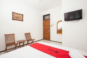 RedDoorz near Sanan Malang في مالانغ: غرفة نوم بسرير وكرسيين وتلفزيون بشاشة مسطحة