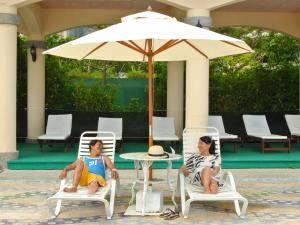 
two people sitting under an umbrella on a patio at Howard Beach Resort Kenting in Kenting
