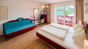 um quarto com uma cama, um sofá e uma mesa em Strandhotel Orchidee em Sankt Kanzian