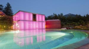 a swimming pool in front of a house with pink lighting at Hotel Germania Gastein - ganzjährig inklusive Alpentherme Gastein in Bad Hofgastein +52 photos