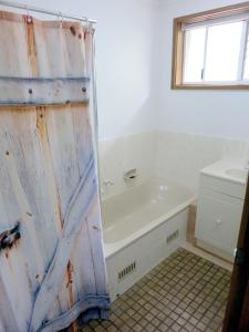 ein Bad mit einer Badewanne und einem Duschvorhang in der Unterkunft A2@Port Willy in Port Willunga