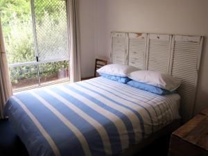 ein Bett mit zwei Kissen und ein Fenster in einem Zimmer in der Unterkunft A2@Port Willy in Port Willunga