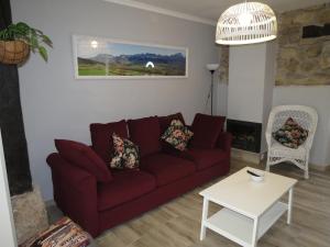 a living room with a red couch and a table at Casa Rural El Setal. in Villasana de Mena