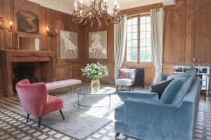 sala de estar con sillas azules y chimenea en Le manoir des chevaux dorés en Le Neubourg