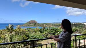 a woman standing on a balcony looking out at the ocean at Howard Beach Resort Kenting in Kenting