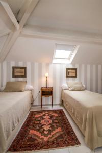 two beds in a room with a rug and a window at Villa Côté Sud in Draguignan