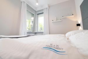 a bedroom with a white bed with a sign on it at Apartament K&K Klifowa Rewal in Rewal +54 photos