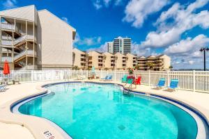een zwembad met stoelen en een gebouw bij Baywatch in Pensacola Beach