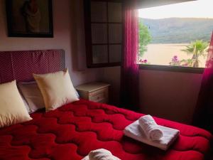 a bedroom with a red bed with towels on it at La Granja del Pescador in Casas del Castañar