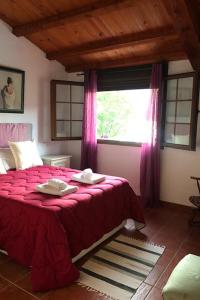 a bedroom with a bed with a red blanket and a window at La Granja del Pescador in Casas del Castañar