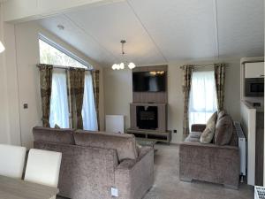 a living room with a couch and a tv at Riverside Rothbury Superior Lodge in Rothbury