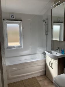 a bathroom with a shower and a tub and a sink at Riverside Rothbury Superior Lodge in Rothbury