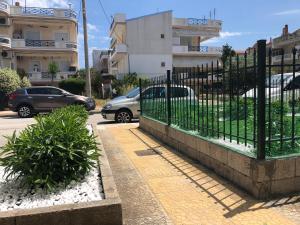 a fence next to a parking lot with parked cars at ORFEAS SUITE in Néa Péramos