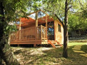 a log cabin with a large deck in the woods at Camping Les Lavandes in Darbres