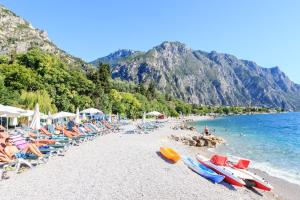 una spiaggia con un mucchio di sedie e barche di Hotel Leonardo Da Vinci a Limone sul Garda