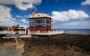 a blue and red house on the shore of the ocean at Beautiful Apartament Arrieta in Haría