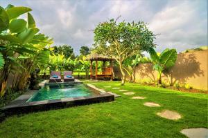 a backyard with a swimming pool in the grass at Three Gold Luxury Private Villas in Ubud