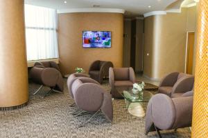 uma sala de espera com cadeiras e uma televisão na parede em Hotel International em Baile Felix