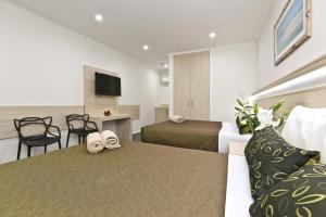 a hotel room with two beds and a table at Morphettville Motor Inn in Glenelg