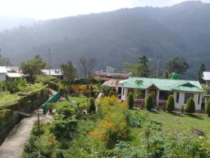 a house in a garden with a mountain in the background at Jharna Homestay - Tabakoshi in Mirik