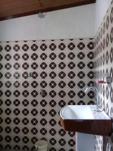ein Badezimmer mit einem Waschbecken und einer schwarz-weiß gefliesten Wand in der Unterkunft Vamoose Jharna Tabakoshi in Mirik