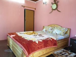 ein Schlafzimmer mit einem Bett mit einer Uhr an der Wand in der Unterkunft Vamoose Jharna Tabakoshi in Mirik