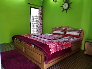 a bedroom with a wooden bed with a green wall at Jharna Homestay - Tabakoshi in Mirik