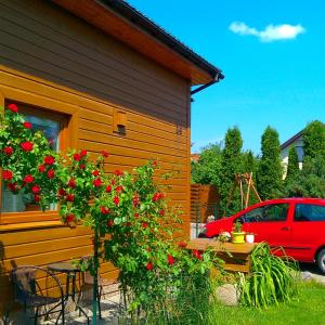 un coche rojo estacionado junto a una casa con flores rojas en Apartamentai Alyvu 14 Palanga, en Palanga