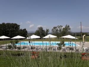 a swimming pool with white umbrellas and chairs and a pool at Agriturismo Poderi Minori in Bibbiena