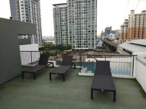 a balcony with three chairs and a view of a city at Apartment at Punnawithi BTS in Bangkok