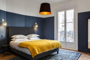 a bedroom with blue walls and a bed with a yellow blanket at Appartement Monceau in Paris