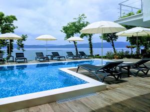 uma piscina com cadeiras e guarda-sóis junto à água em Golden Sunset Apartments em Ohrid
