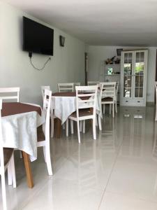 a dining room with white tables and chairs and a flat screen tv at Pensiunea Calea Targovetilor in Târgovişte