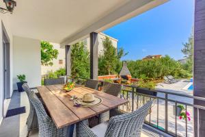 a patio with a wooden table and chairs on a balcony at Apartment Villa Hacijenda with private pool and jacuzzi in Kaštela