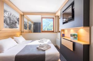 a hotel room with two beds and a flat screen tv at Hôtel Club mmv Les Brévières **** in Tignes