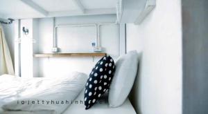 Jetty Huahin Hostel في هوا هين: سرير مع ملاءات بيضاء ووسائد polka dot