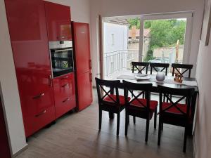 eine Küche mit roten Schränken und einem Tisch mit Stühlen in der Unterkunft Apartment im Herzen von Neustrelitz in Neustrelitz