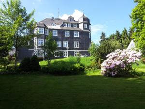 ein großes Haus mit einem großen Garten mit Blumen in der Unterkunft Pension Haus am Waldesrand in Oberhof