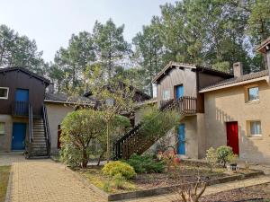 una casa con una puerta roja y escaleras en Apartment Hameau du golf-2 by Interhome, en Lacanau-Océan