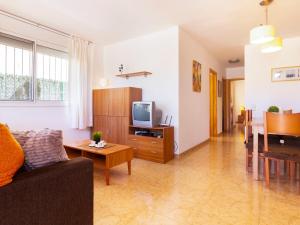 ein Wohnzimmer mit einer Couch, einem Fernseher und einem Tisch in der Unterkunft Holiday Home Flamenc 2 by Interhome in Riumar