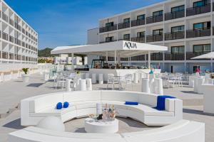 eine Terrasse mit weißen Möbeln vor einem Gebäude in der Unterkunft Hotel Vibra Mare Nostrum in Playa d'en Bossa