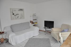 a living room with a white couch and a tv at Ferienwohnung Fischer in Frickingen
