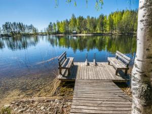two benches sitting on a dock on a lake at Holiday Home Patu by Interhome in Pihlajaniemi