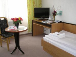 a hotel room with a desk and a bed at Waldhotel Seelow in Seelow